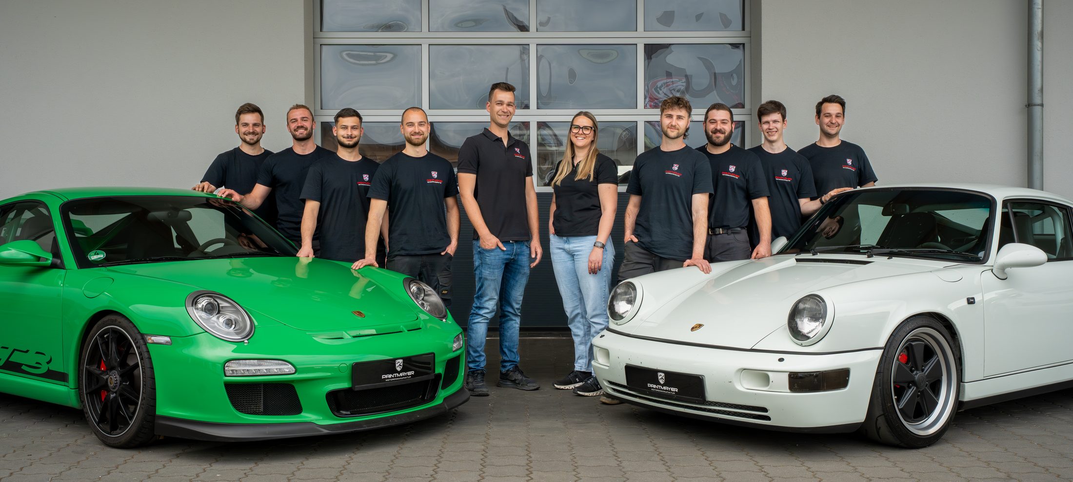 Das Team der Paintmayer Motorenmanufaktur zwischen einem Porsche 911 GT3 und einem 993