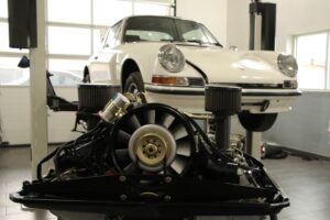Motorrevision Porsche 911 2.2l E Der Porschemotor 911 2.2l E wurde komplett überarbeitet. Das Hauptlagergasse wurde auf Übermaß gespindelt und komplett neu gelagert. Zylinderköpfe wurden geplant, Glasperlen gestrahlt, die Ventilführungen erneuert und die Ventilsitze nachgeschnitten. Auch die Ventilfedern wurden neu eingemessen und der Motor bekam neue Kolben und Zylinder des Porsche 911 2.4 S Mahle. Die Einzeldrosselklappenanlage haben wir neu justiert. Neu eingestellt und geprüft wurde die Einspritzpumpe und im Anschluss der Motor mit dem Auto abgestimmt. Zahnräder der Nockenwelle und Zwischenwelle haben wir durch neue ersetzt. Nachdem die Lichtmaschine überholt wurde bekam der 911er noch eine neue Ölpumpe und Ölkühler. Standardgemäß werden bei einer Motorrevision Porsche 911 alle Schrauben und Gestänge Gold galvanisiert und das Lüfterrad neu gelagert und in Wunschfarbe lackiert. Der Motor läuft wieder rund und das tolle Fahrerlebnis mit dem 911er kann wieder los gehen.