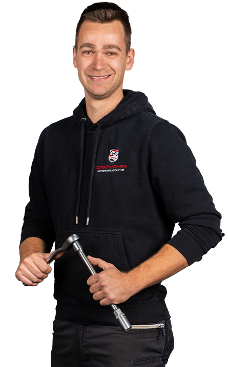 Ein lächelnder Mann in einem schwarzen Kapuzenpulli, der einen Ratschenschlüssel hält, steht vor einem weißen Hintergrund.