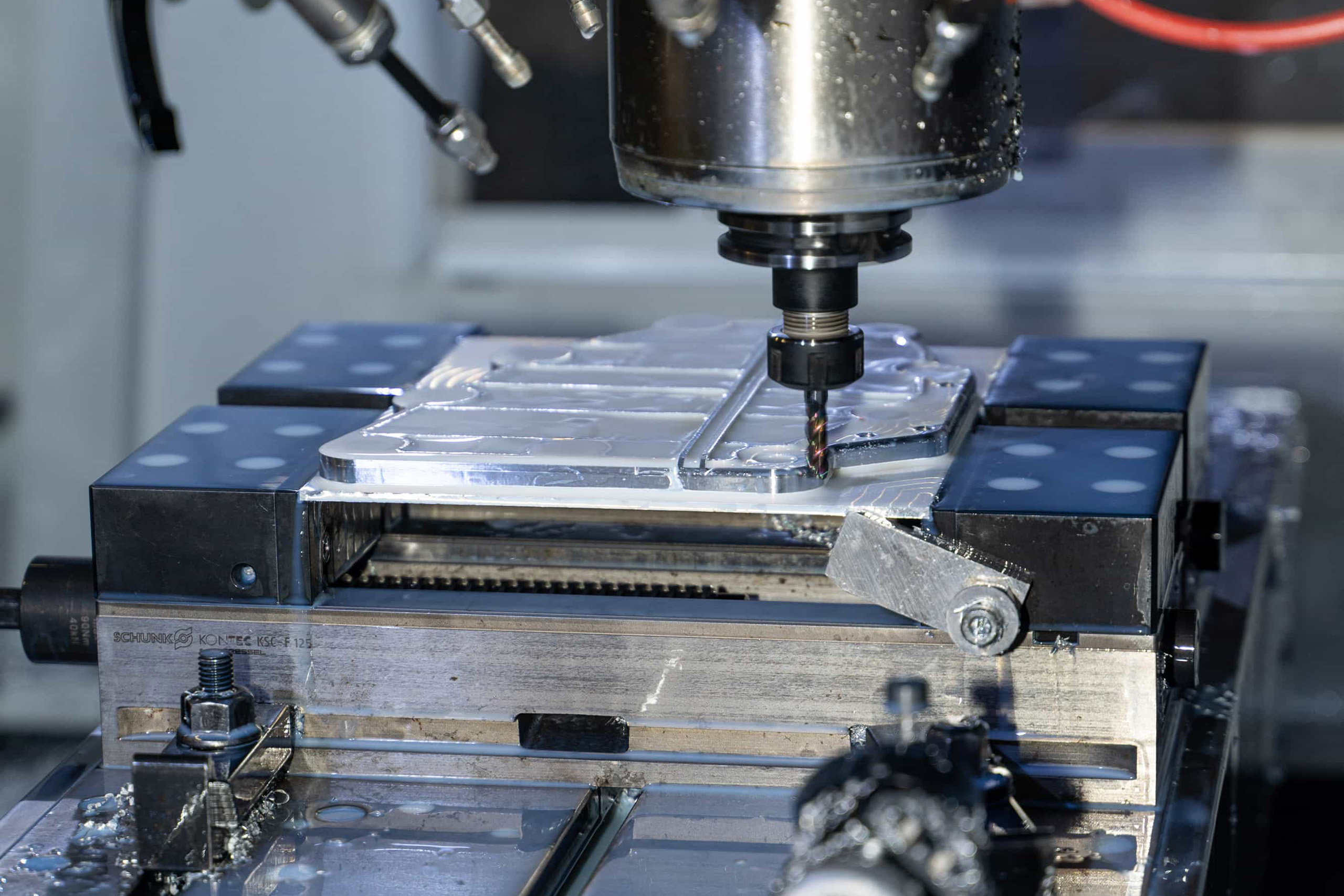 paintmayer_fräsen©invisions Nahaufnahme eines Automotors mit einem schwarzen Riemen mit der Aufschrift "Porsche", der um Metallscheiben und einen Lüfter gewickelt ist, wobei im Hintergrund Details der Motorkomponenten sichtbar sind.