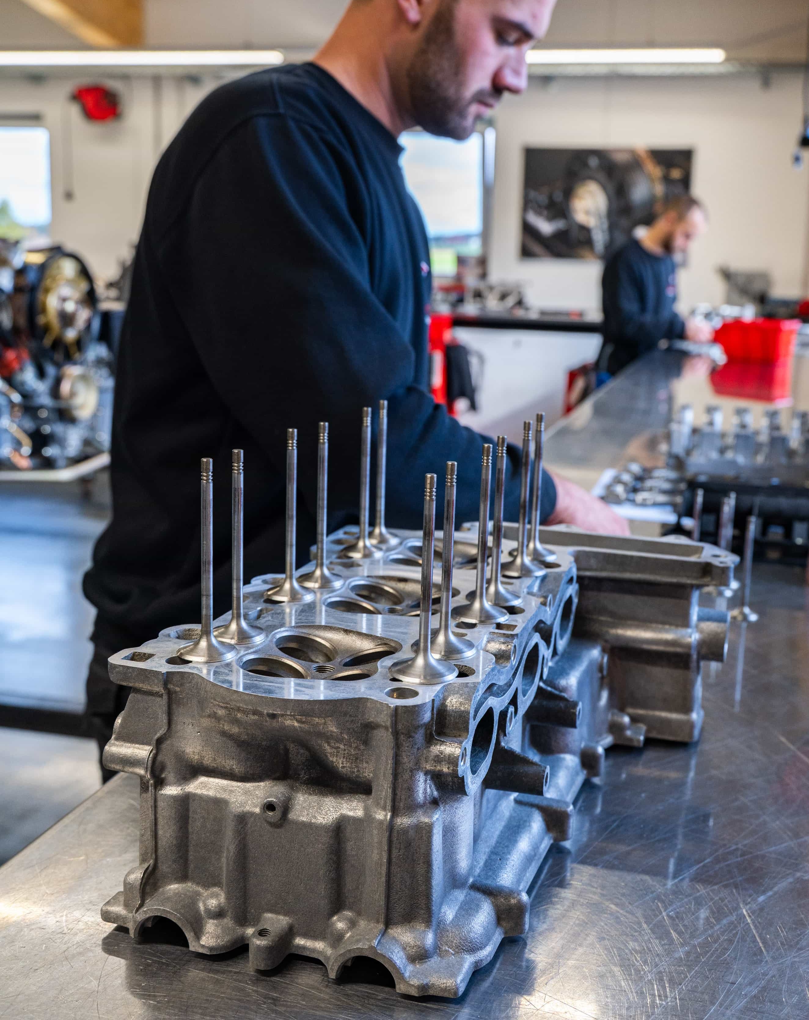 paintmayer_manufaktur_porsche_143©invisions.at Eine Person, die auf dem Fahrersitz eines grünen Sportwagens sitzt, verwendet einen Laptop, auf dem bunte Datentabellen und ein 3D-Diagramm angezeigt werden, um möglicherweise die Leistung des Fahrzeugs zu optimieren.